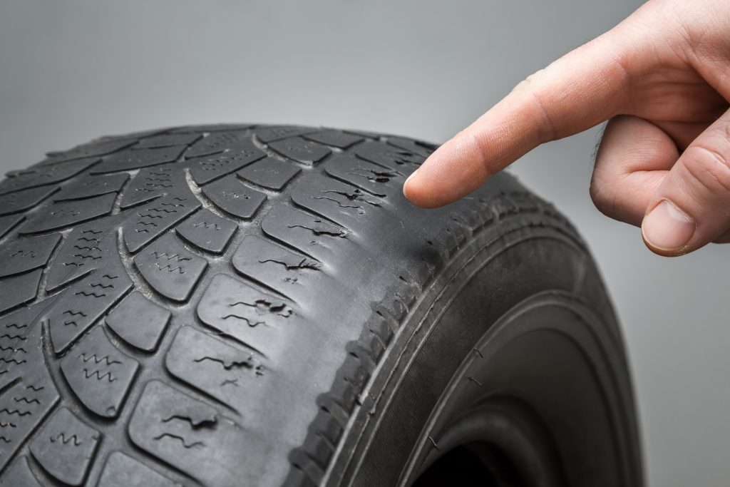 A hand pointing to a tyre to show worn tread